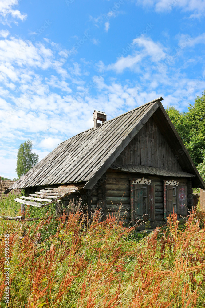 old wooden house in the abandoned village in the green grass under blue summer sky old wooden house in the abandoned village in the green grass under blue summer sky
