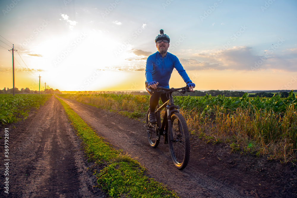cyclist on bike rides along the fields of wheat in the sunlight. sports and hobbies. outdoor activities cyclist on bike rides along the fields of wheat in the sunlight. sports and hobbies. outdoor activities