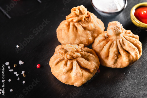 Appetizing traditional fried khinkali on a dark background among spices and sauces. Traditional food concept photo