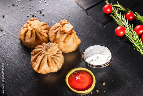 Appetizing traditional fried khinkali on a dark background among spices and sauces. Traditional food concept