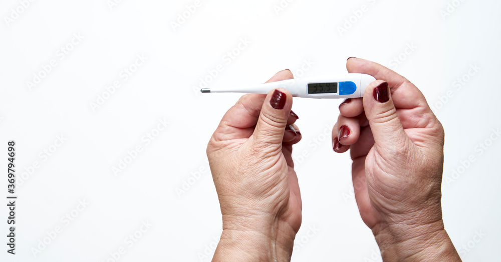 Old woman hands holding digital thermometer to measure body temperature. Means of coronavirus prevention and treatment. Covid-19. Concept of health. Old woman hands holding digital thermometer to measure body temperature. Means of coronavirus prevention and treatment. Covid-19. Concept of health.