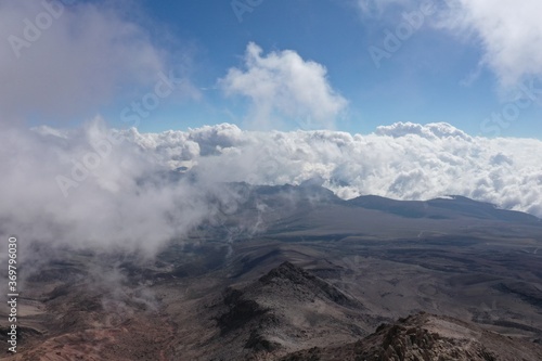 Aerial view of a mountainous landscape and a white cloudscape, taken from within the clouds