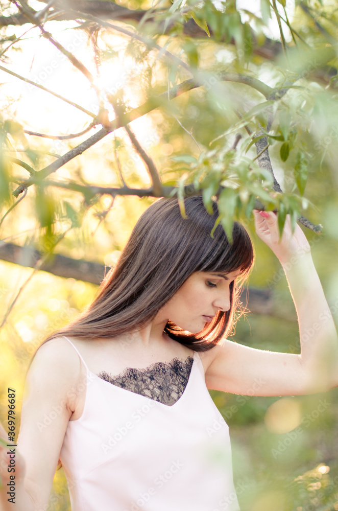 Attractive young woman outside in park with sunset in background Attractive young woman outside in park with sunset in background