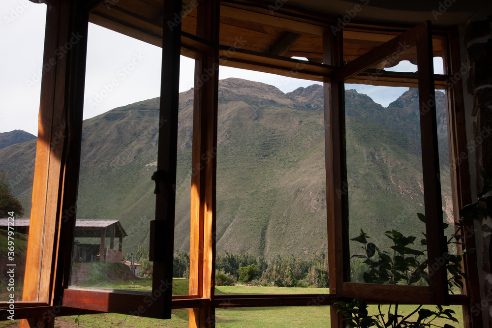 Fototapeta premium Large glass windows that are opened and have a beautiful view on a large with grass covered mountain