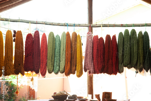 Wool dyed in different colors with natural paint that is hung up to dry on a wooden stick