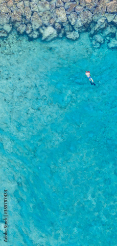 An aerial view of the beautiful Mediterranean Sea and a swimmer  where you can see   the cracked rocky textured underwater corals and the clean turquoise water of Protaras  Cyprus  