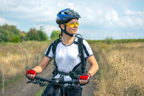 Beautiful and happy girl cyclist with a bike on nature. Healthy lifestyle and sports. Leisure and hobbies