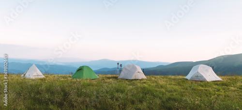 Four tents on amazing meadow in summer mountains. Tourists camp. Landscape photography  travel concept