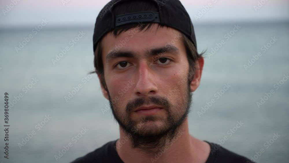 Portrait of african asian male wearing hat standing outdoors along the beach.light reflects on his face Portrait of african asian male wearing hat standing outdoors along the beach.light reflects on his face
