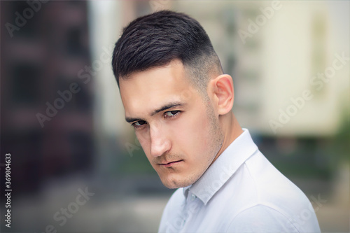 Close up portrait of serious upset handsome man, young sad frustrated offended guy looking at camera sullenly with confident look outdoors photo