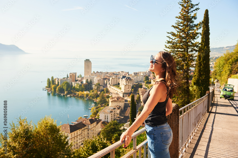 Young beautiful woman tourist admiring amazing view of Montreux city, Switzerland, canton of Vaud
