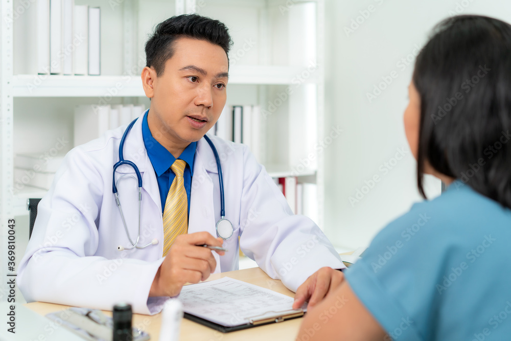 Asian man doctor and woman patient are discussing consultation about symptom problem diagnosis of disease talk to the patient about medication and treatment method.. Asian man doctor and woman patient are discussing consultation about symptom problem diagnosis of disease talk to the patient about medication and treatment method..