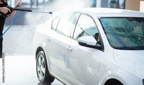 Summer car wash. Cleaning the car using high pressure water. Car wash with soap. Close up concept. Close up photo of a man hands washes his car Concept disinfection and antiseptic cleaning. Car wash.