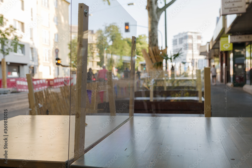 Selected focus at temporary transparent plastic partition on outdoor table to make Social Distancing for customer of restaurant or cafe during epidemic of COVID-19 in Düsseldorf, Germany. Selected focus at temporary transparent plastic partition on outdoor table to make Social Distancing for customer of restaurant or cafe during epidemic of COVID-19 in Düsseldorf, Germany.