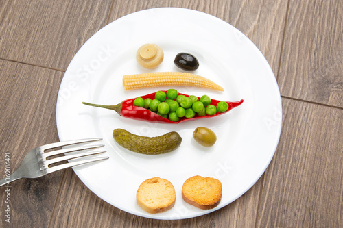 salad of canned and pickled olives, mushrooms, corn, peas, cucumber and red pepper on a white plate. food and vegetables. diet and weight loss