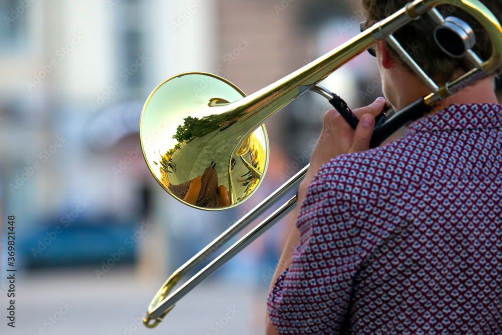 Fototapeta premium Reflection of the street in the instrument solo trumpet. male musician plays the trombone. music and creativity. jazz and Blues