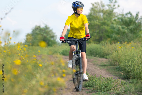 beautiful and happy girl cyclist rides a bicycle on the road in nature. Healthy lifestyle and sports. Leisure and hobbies
