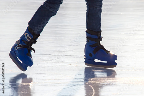 Legs of a man skating on an ice rink. Hobbies and sports. Vacations and winter activities. photo