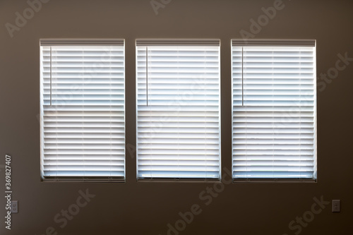 Fotografija Three windows with closed modern white wood faux window blinds as background