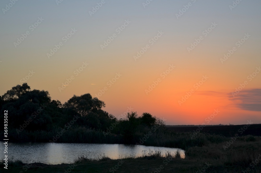 Natural silhouetted landscape. Sunset sky and two flying planes over the pond to the left. Natural silhouetted landscape. Sunset sky and two flying planes over the pond to the left.