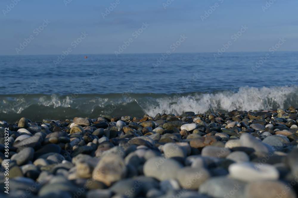 Seascape, view from the pebble shore on the rushing swirling wave.