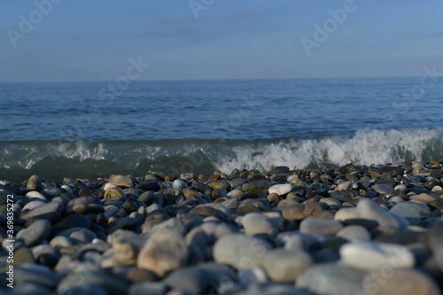 Seascape, view from the pebble shore on the rushing swirling wave.