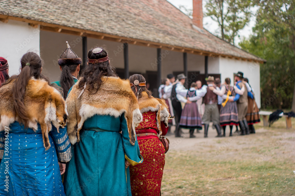 pagan, Hungarian Conquest suit wearers watching at Hungarian folk dancers in Ópusztaszer