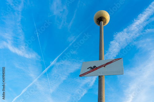 old "no swimming" sign on a street lamp in front of the blue sky