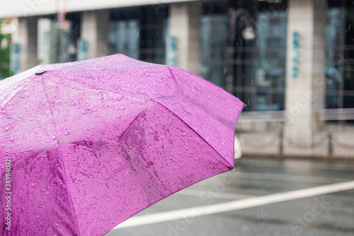 Bad weather. Rainy day. Umbrella with raindrops on the city background. City street style.