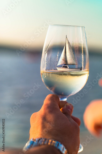 sailing ship in a glass of wine, sailing boat inside of a glass at sunset in summer