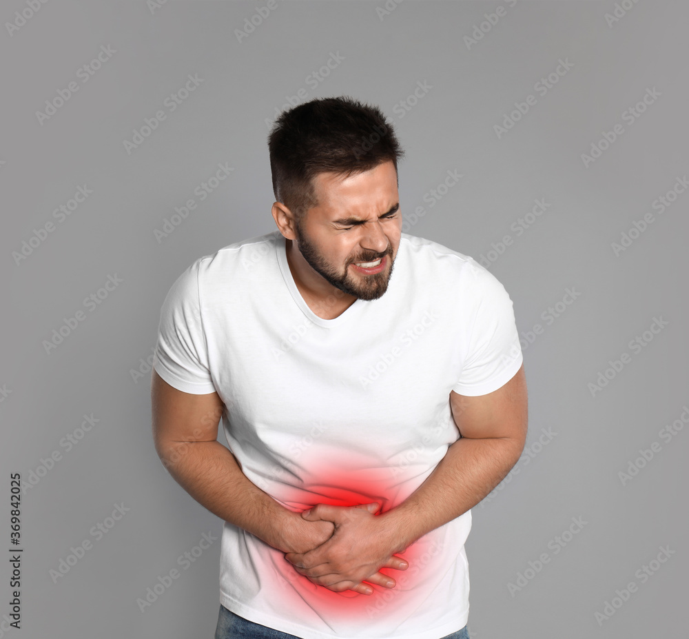 Man suffering from abdominal pain on grey background Man suffering from abdominal pain on grey background