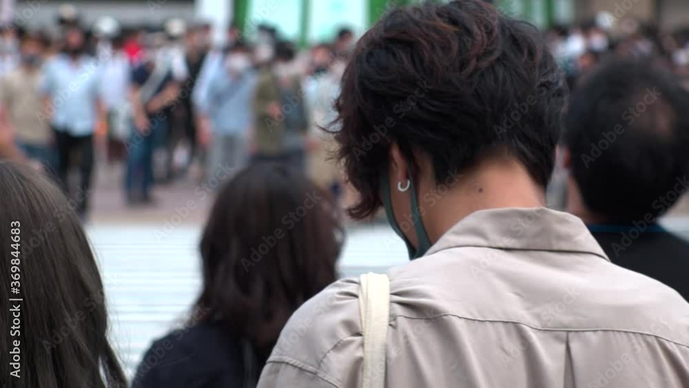 SHIBUYA, TOKYO, JAPAN - AUG 2020 : Back shot and crowd of people wearing surgical mask to protect from Coronavirus (COVID-19) at Shibuya Crossing. Shot in day time, hot summer season. Slow motion.