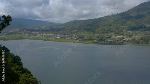 Aerial through trees to a view over Lake Bratan and the surrounding areas of the Bedugul resort region of Bali. Drone forward motion photo