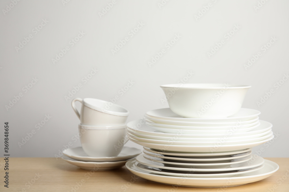 Clean plates, bowl and cups on wooden table against white background. Space for text - obrazy, fototapety, plakaty 