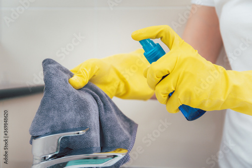 Bild auf Leinwand Woman house keeper cleaning a dirty stainless water tap on the wash basin in toilet