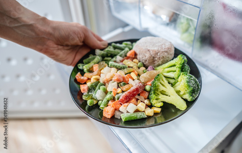 Cuadro en lienzo Hands are taking a plate of frozen food out of the freezer of the fridge