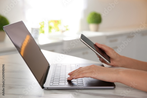 Woman working with modern laptop at marble table, closeup