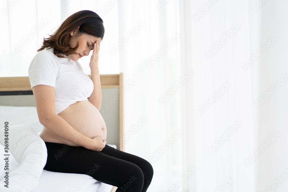 Upset and crying pregnant woman sitting on the bed. Depressing suffer in pregnant woman with her husband. Problem in marriage life between husband and wife. Upset and crying pregnant woman sitting on the bed. Depressing suffer in pregnant woman with her husband. Problem in marriage life between husband and wife.