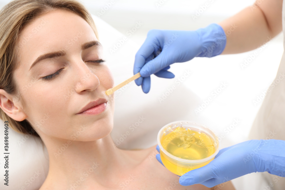 Beautiful woman getting wax epilation of face in salon Beautiful woman getting wax epilation of face in salon