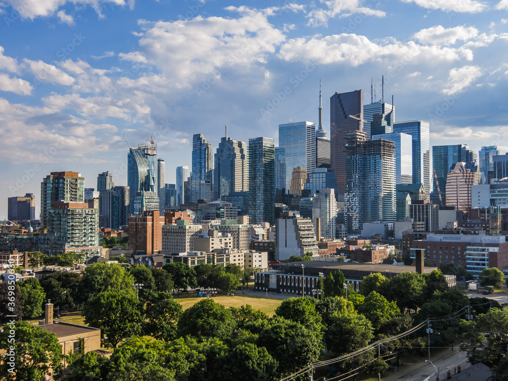 Obraz premium Downtown Toronto Skyline: wieżowce dzielnicy finansowej z niebieskim pochmurnym niebem w tle i parkiem na dole