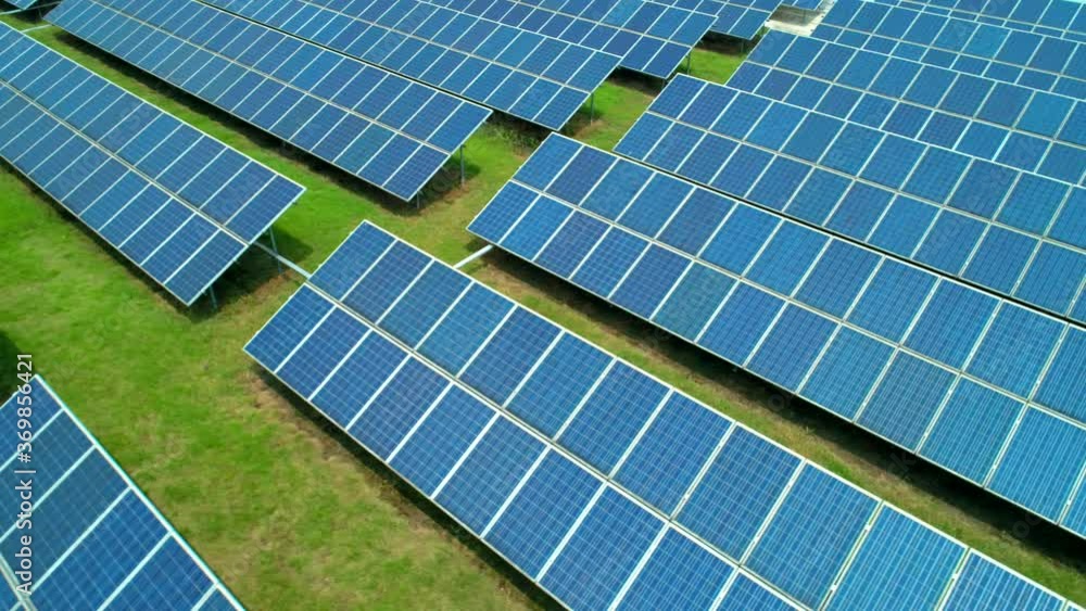 Aerial view of Solar Panels Farm (solar cell) with sunlight. Production of clean energy. Renewable green alternative energy concept. Camera moves left.