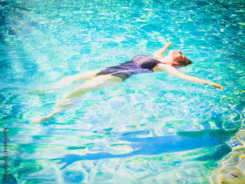 Woman lying on clear water at tropical beach. beautiful mature girl lying and enjoying in water and relaxing