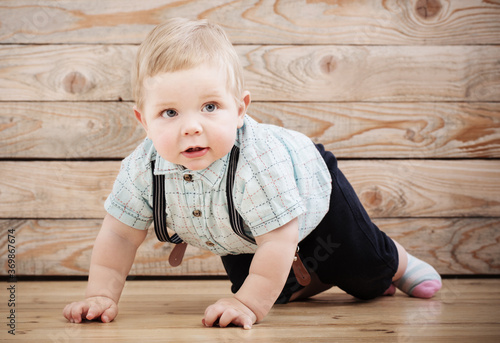 baby in shirt and suspenders shorts on wooden background