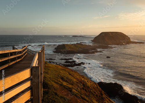 Boardwalk leading to the ocean, with islands and the water at sunset