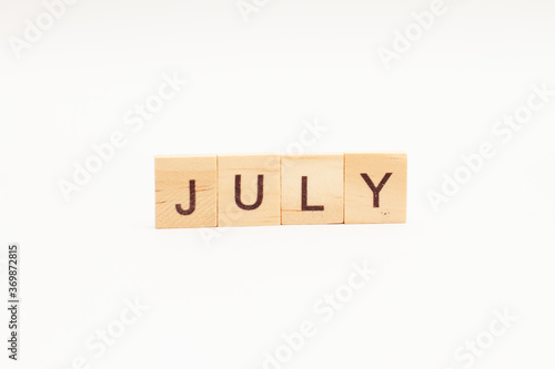 Word JULY made of wooden blocks on white background. Month of year