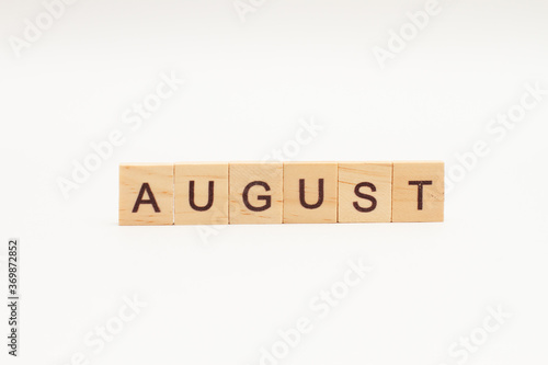 Word AUGUST made of wooden blocks on white background. Month of year. The end of the summer