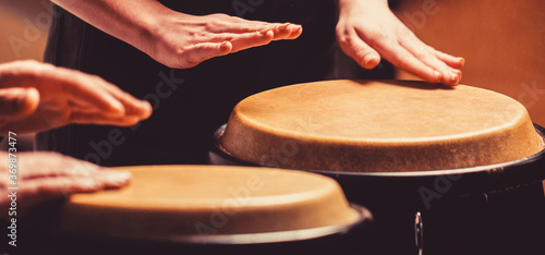 Close up of musician hand playing bongos drums. rum. Hands of a musician playing on bongs. The musician plays the bongo photo
