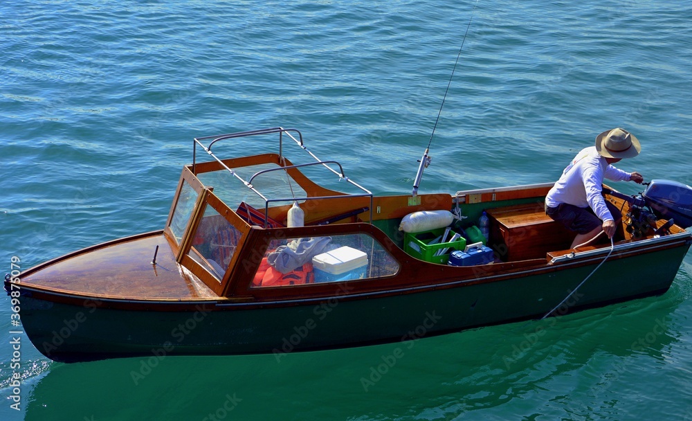 fisherman on a motor, wooden boat with a fishing rod