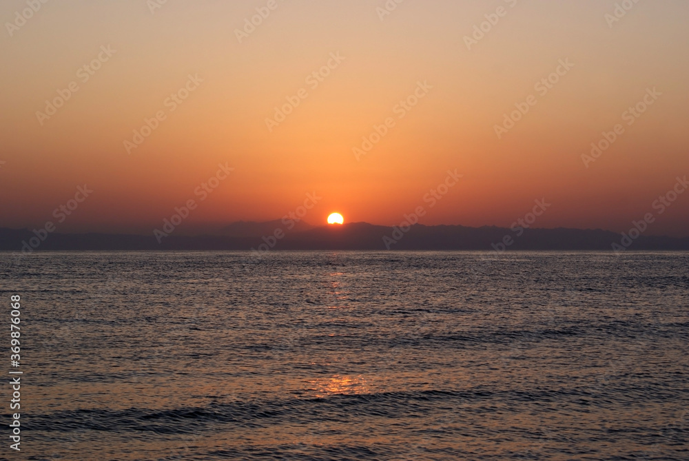 Fototapeta premium Beautiful dawn over the sea. Sunny path on the water. Light wave and swell on the surface of the water
