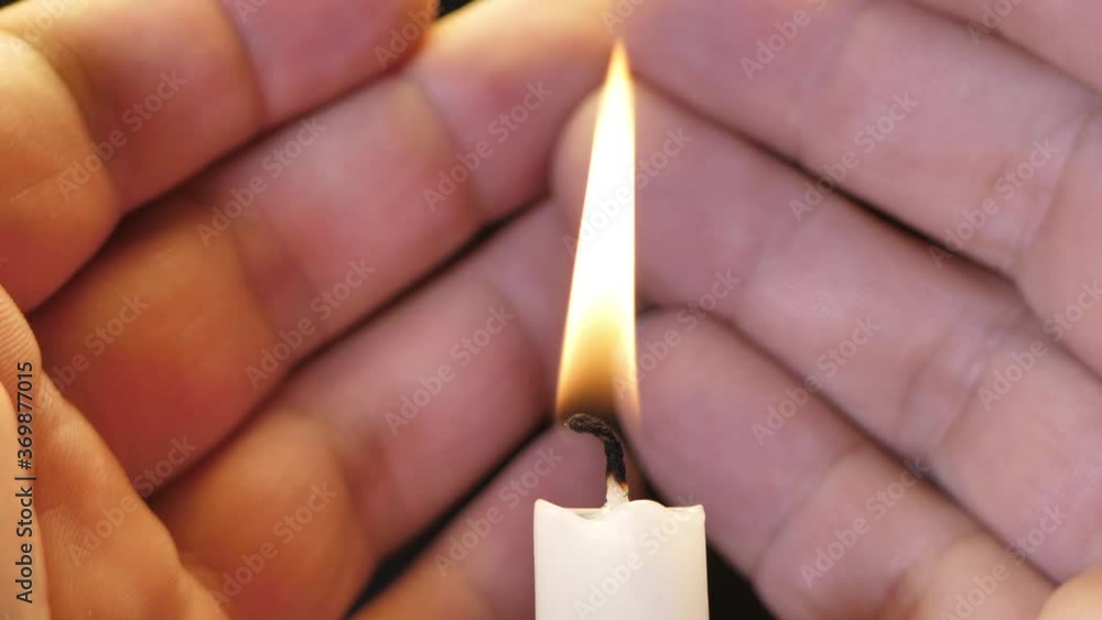 Candle flame close-up on a black background, the candle has gone out white smoke is visible, the man's hands are praying Candle flame close-up on a black background, the candle has gone out white smoke is visible, the man's hands are praying